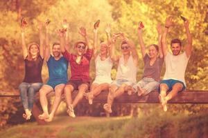 friends enjoying watermelon while sitting on the wooden bridge photo