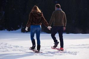 couple having fun and walking in snow shoes photo