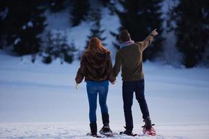 pareja divirtiéndose y caminando con raquetas de nieve foto