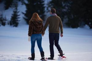 pareja divirtiéndose y caminando con raquetas de nieve foto