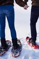 pareja divirtiéndose y caminando con raquetas de nieve foto