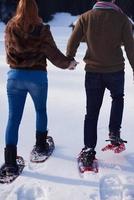 pareja divirtiéndose y caminando con raquetas de nieve foto