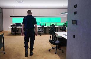 young male security operator walking through data system control room photo