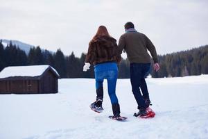 pareja divirtiéndose y caminando con raquetas de nieve foto