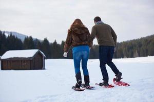 pareja divirtiéndose y caminando con raquetas de nieve foto