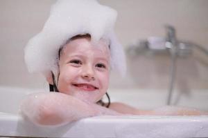 niña en el baño jugando con espuma de jabón foto