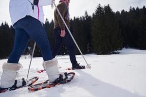 couple having fun and walking in snow shoes photo