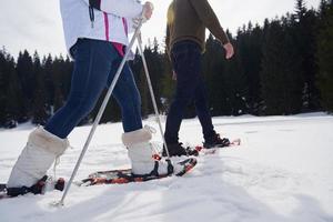 pareja divirtiéndose y caminando con raquetas de nieve foto