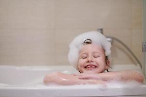 niña en el baño jugando con espuma de jabón foto