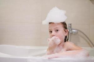 little girl in bath playing with soap foam photo