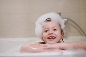 niña en el baño jugando con espuma de jabón foto