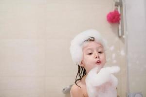 niña en el baño jugando con espuma de jabón foto