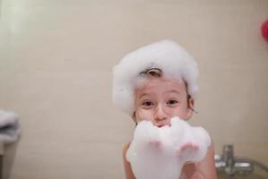 little girl in bath playing with soap foam photo