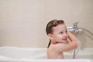 little girl in bath playing with soap foam photo