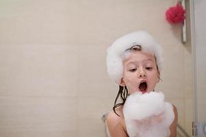 niña en el baño jugando con espuma de jabón foto