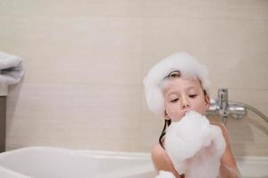 niña en el baño jugando con espuma de jabón foto