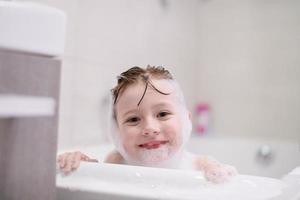 niña en el baño jugando con espuma de jabón foto