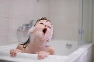 niña en el baño jugando con espuma de jabón foto