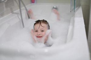 little girl in bath playing with soap foam photo