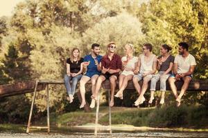 amigos disfrutando de la sandía mientras están sentados en el puente de madera foto