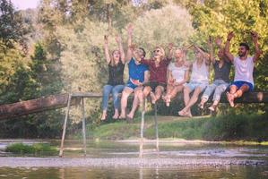 friends enjoying watermelon while sitting on the wooden bridge photo