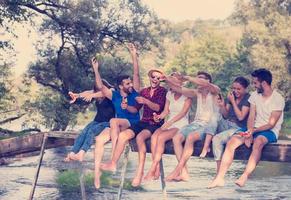 friends enjoying watermelon while sitting on the wooden bridge photo