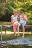 pareja disfrutando de la sandía mientras se sienta en el puente de madera foto