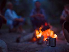 young friends relaxing around campfire photo