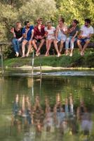 friends enjoying watermelon while sitting on the wooden bridge photo