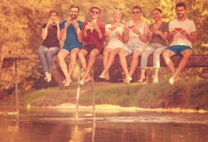 amigos disfrutando de la sandía mientras están sentados en el puente de madera foto