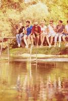 friends enjoying watermelon while sitting on the wooden bridge photo