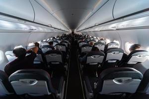 Airplane cabin seats with passengers. Economy class of new cheapest low-cost airlines without delay or cancellation of flight. Travel trip to another country. photo