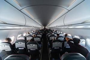 Airplane cabin seats with passengers. Economy class of new cheapest low-cost airlines without delay or cancellation of flight. Travel trip to another country. photo