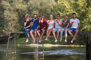 amigos disfrutando de la sandía mientras están sentados en el puente de madera foto