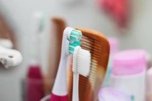 cepillo de dientes, peine, maquinilla de afeitar están en el vaso, colocados en el baño frente al espejo. foto