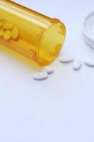 Oval pills and orange pill bottles were spread out on the white tabletop. photo