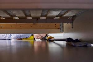 Woman cleaning floor under bed using flat wet mop. photo