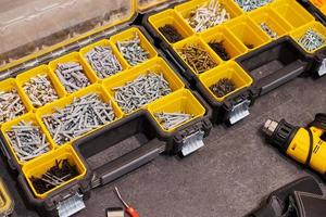 Storage boxes on floor with screws, nuts, bolts, nails and other small tools for handyman, close up photo