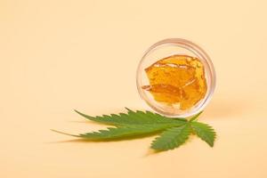 high thc, pieces of yellow cannabis wax and green leaf, marijuana concentrate photo