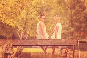 pareja disfrutando de la sandía mientras se sienta en el puente de madera foto