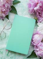 Flat lay paper notebook, eyeglasses, peony flowers photo