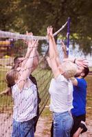 group of young friends playing Beach volleyball photo