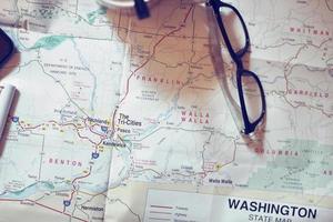 Map, map of Washington state, pen, glasses, cell phone, coffee cup on the table. photo