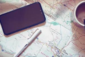 Map, map of Washington state, pen, glasses, cell phone, coffee cup on the table. photo