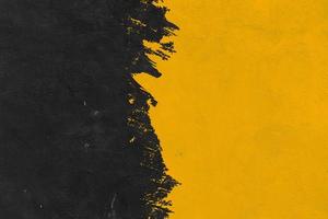 fondo de textura de pincel negro y amarillo. fondo de pincelada abstracta, formas planas. en una pared de hormigón foto