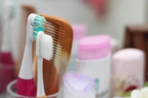 Toothbrush, comb, razor are in the glass, placed in the bathroom in front of the mirror. photo