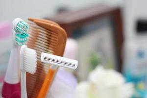 cepillo de dientes, peine, maquinilla de afeitar están en el vaso, colocados en el baño frente al espejo. foto