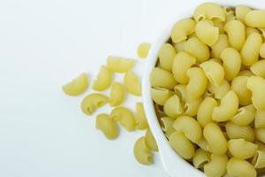 Macaroni raw in white bowl on white background. photo