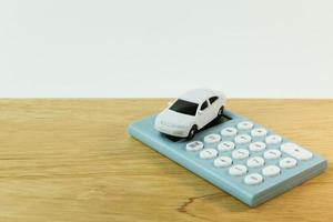 juguete de coche blanco y fondo blanco calculadora azul. foto