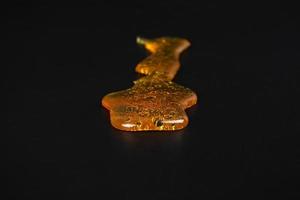 golden cannabis wax resin smear on dark background photo